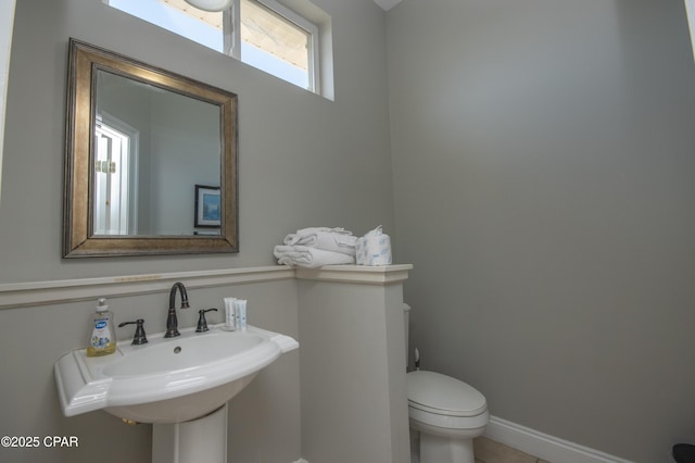 bathroom with a sink, baseboards, and toilet