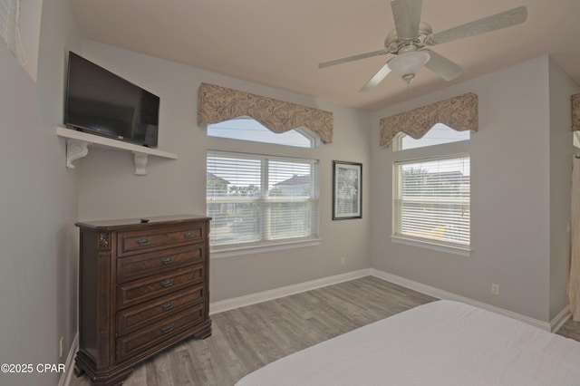 bedroom featuring baseboards, wood finished floors, and a ceiling fan