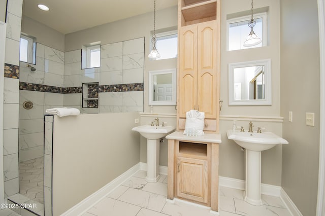 full bathroom with marble finish floor, two sinks, baseboards, and walk in shower