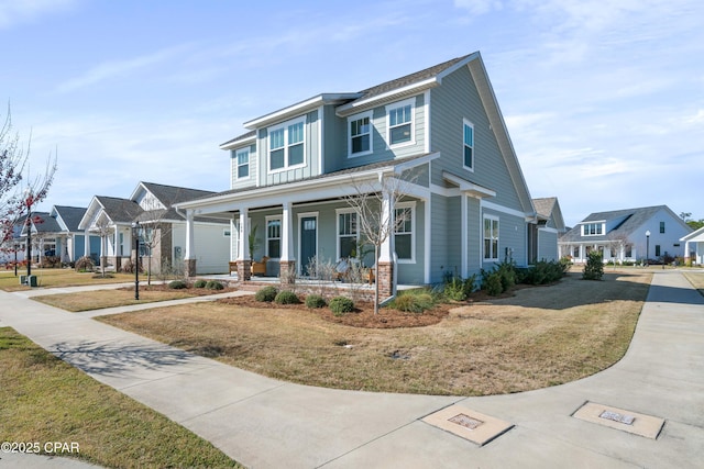 view of front of property featuring a front lawn, driveway, covered porch, and a residential view