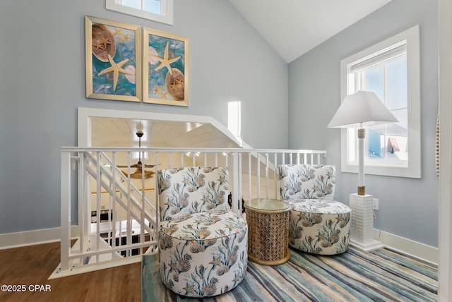 living area with an upstairs landing, wood finished floors, baseboards, and vaulted ceiling