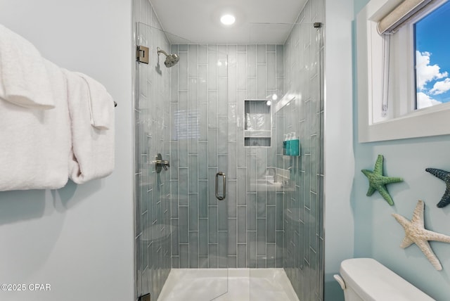 bathroom featuring toilet and a shower stall