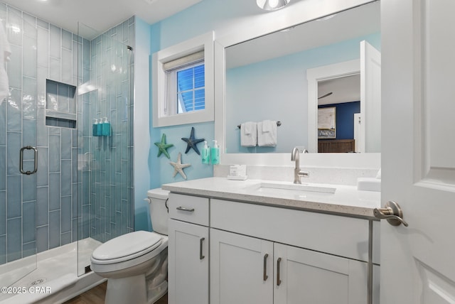 bathroom with vanity, a shower stall, and toilet