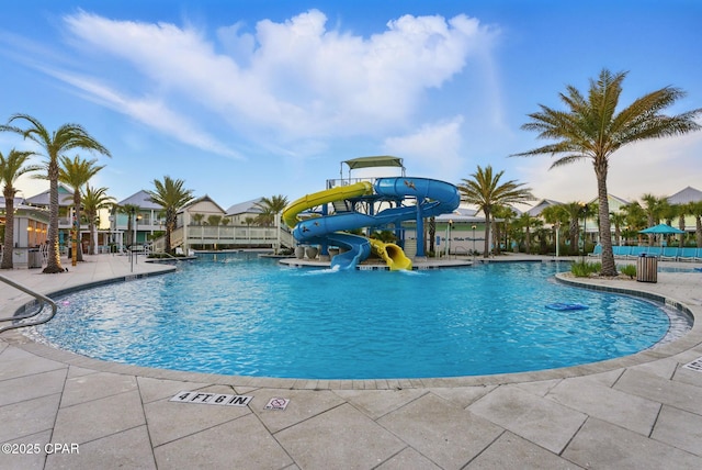 pool featuring a patio area, a water slide, and fence