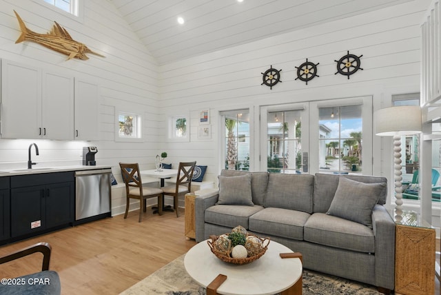 living area with light wood-style floors, a healthy amount of sunlight, and high vaulted ceiling