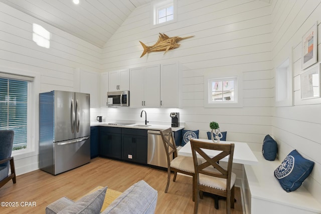 kitchen featuring light countertops, appliances with stainless steel finishes, light wood-style floors, high vaulted ceiling, and a sink