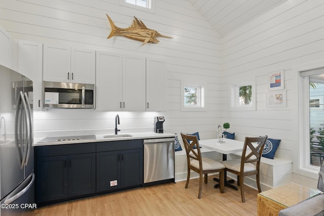 kitchen with appliances with stainless steel finishes, breakfast area, light countertops, and a sink