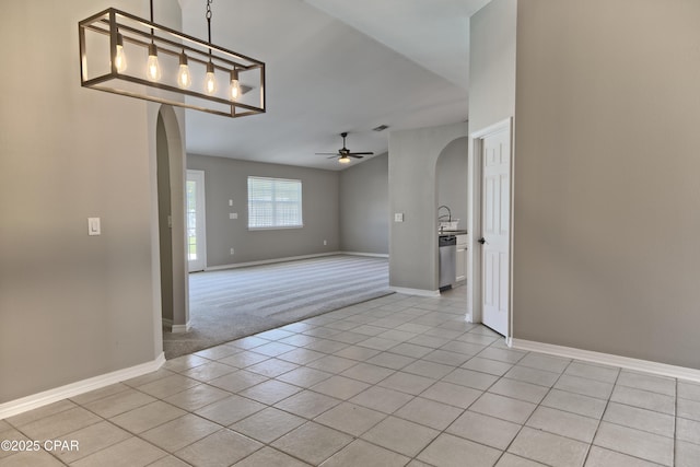 empty room featuring light tile patterned floors, arched walkways, and a ceiling fan