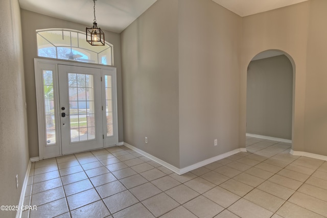 entrance foyer with light tile patterned floors, arched walkways, and baseboards