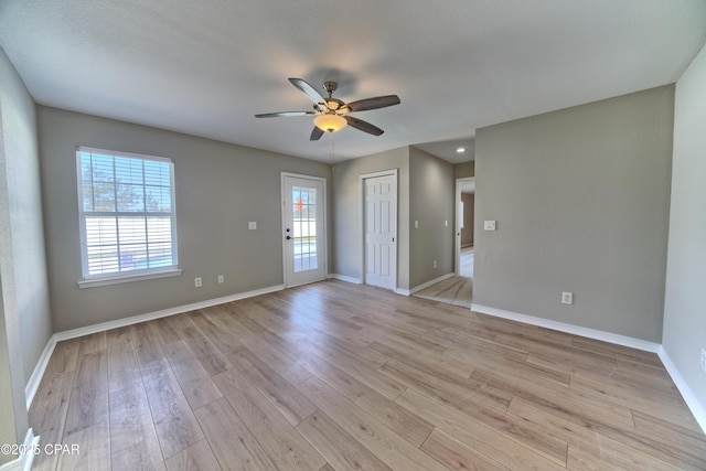 unfurnished room featuring light wood-type flooring, baseboards, and a ceiling fan