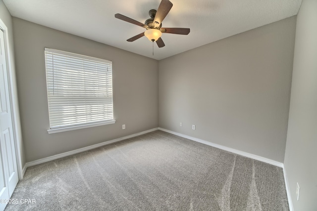 carpeted spare room with baseboards and ceiling fan