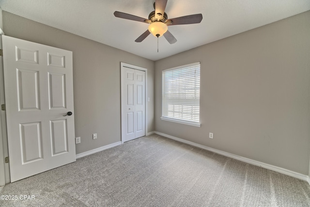 unfurnished bedroom with a ceiling fan, carpet, baseboards, and a closet