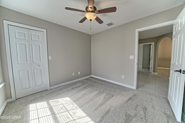 unfurnished bedroom featuring visible vents, ceiling fan, baseboards, carpet, and arched walkways