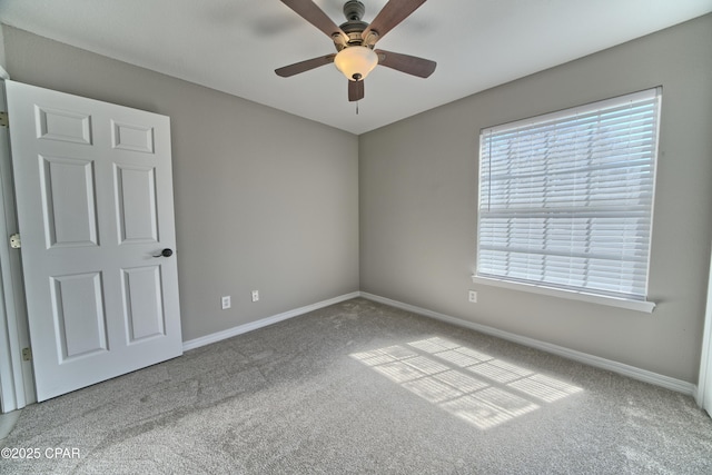 carpeted spare room with baseboards and a ceiling fan