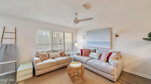 living room featuring visible vents, a textured ceiling, wood finished floors, baseboards, and ceiling fan