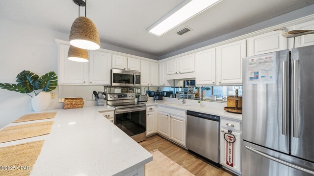 kitchen featuring visible vents, a peninsula, a sink, light countertops, and appliances with stainless steel finishes