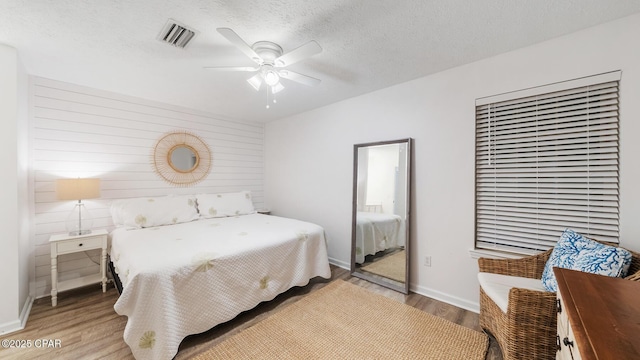 bedroom with visible vents, baseboards, ceiling fan, light wood-style floors, and a textured ceiling