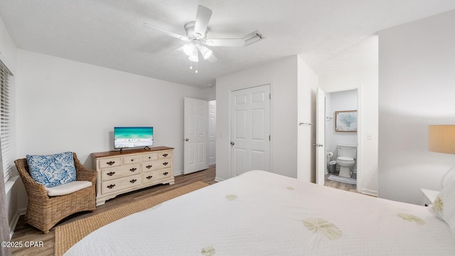 bedroom with ceiling fan, visible vents, ensuite bath, and wood finished floors