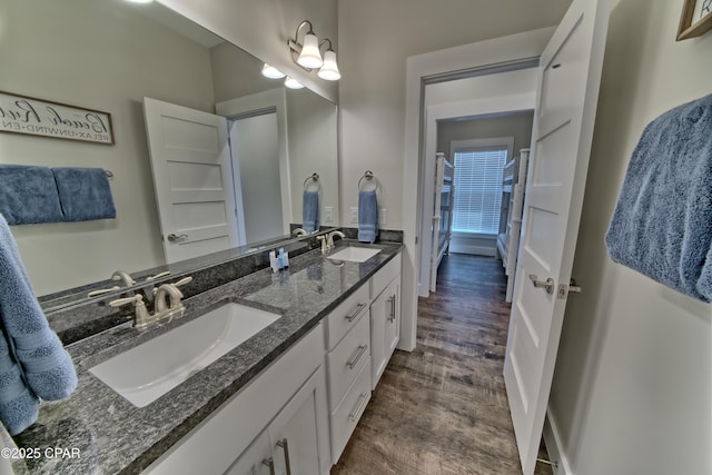 bathroom with double vanity, wood finished floors, and a sink