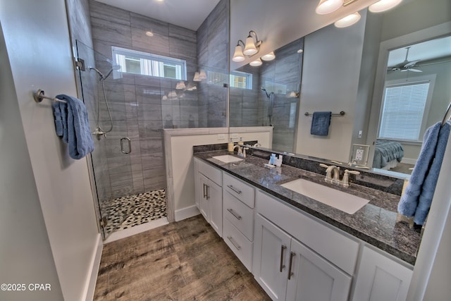 ensuite bathroom with a sink, a shower stall, wood finished floors, and ensuite bathroom