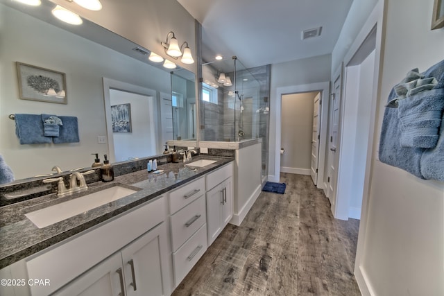 full bathroom with a shower stall, wood finished floors, visible vents, and a sink