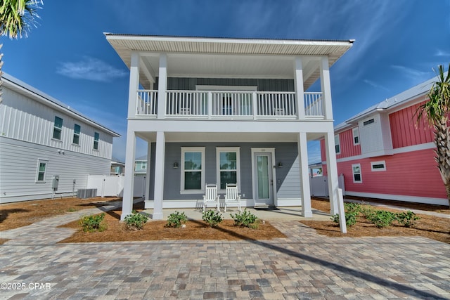 view of front of home with board and batten siding, a balcony, covered porch, and central AC