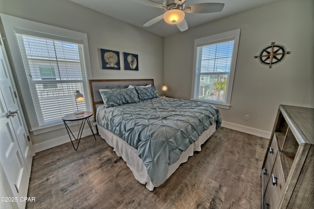 bedroom with dark wood-style floors, multiple windows, and baseboards