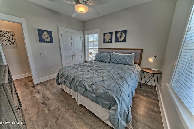 bedroom with baseboards, dark wood-style flooring, a closet, and ceiling fan