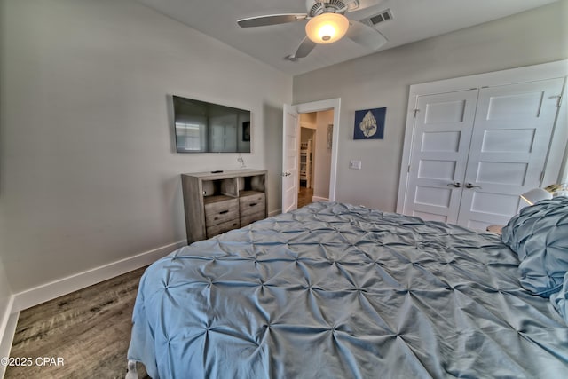 bedroom with visible vents, ceiling fan, baseboards, wood finished floors, and a closet