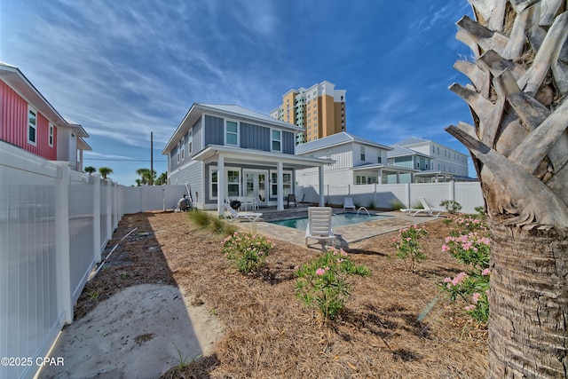 rear view of house with a patio area, a fenced in pool, board and batten siding, and a fenced backyard