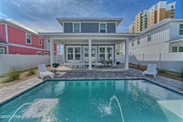 rear view of property with a fenced in pool, a patio, board and batten siding, and a fenced backyard