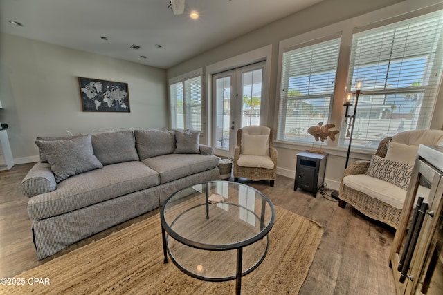 living area with recessed lighting, french doors, baseboards, and wood finished floors