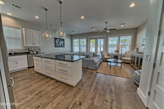 kitchen featuring visible vents, dark wood-type flooring, stainless steel dishwasher, dark countertops, and white cabinets