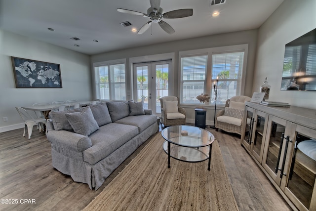 living area featuring visible vents, a healthy amount of sunlight, wood finished floors, and french doors