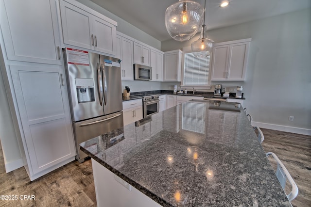 kitchen with dark wood-style flooring, a sink, white cabinets, appliances with stainless steel finishes, and a center island