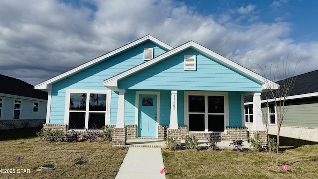 view of front of home with a porch, brick siding, and a front yard