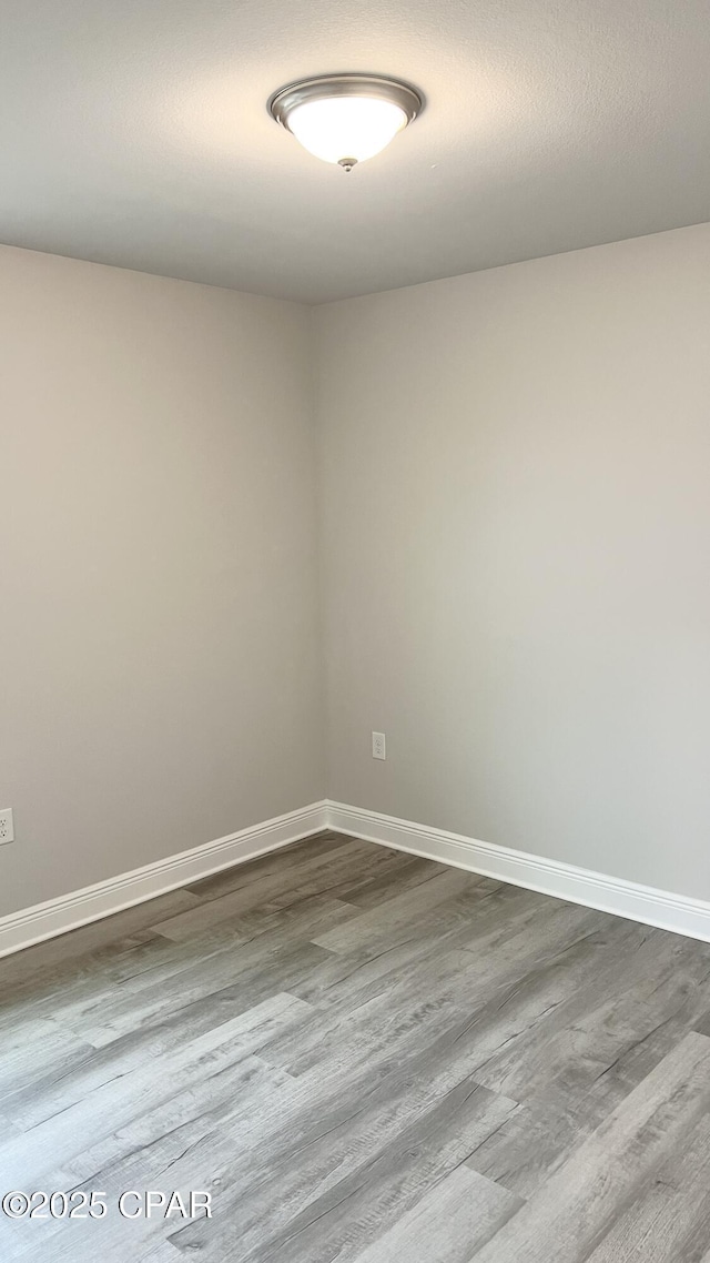 unfurnished room featuring baseboards and dark wood-style flooring