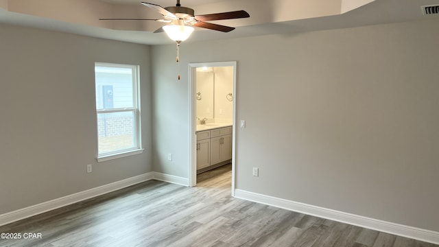 spare room featuring visible vents, baseboards, ceiling fan, light wood-style floors, and a sink