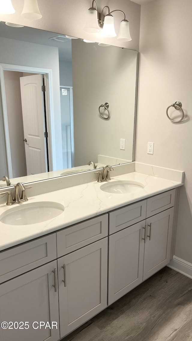 bathroom with double vanity, wood finished floors, and a sink