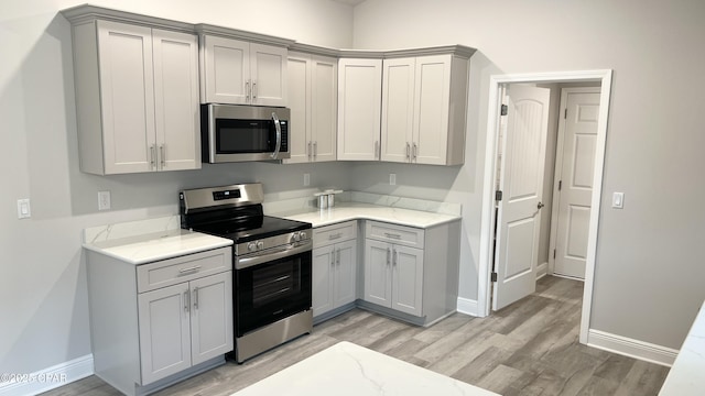 kitchen featuring light wood-style floors, appliances with stainless steel finishes, and gray cabinetry