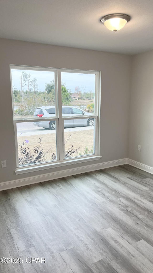 unfurnished room featuring baseboards and wood finished floors