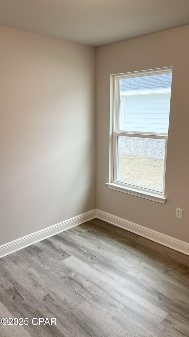 spare room featuring baseboards and wood finished floors