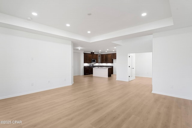 unfurnished living room with light wood-style flooring, recessed lighting, and a sink