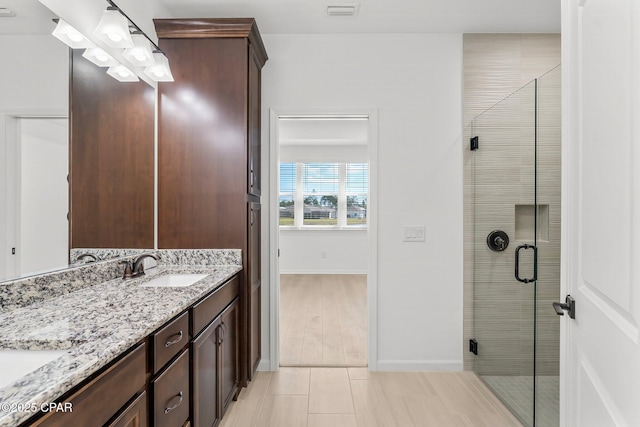 bathroom with double vanity, a stall shower, tile patterned floors, and a sink