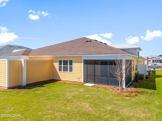 back of property featuring a lawn, driveway, roof with shingles, and a sunroom