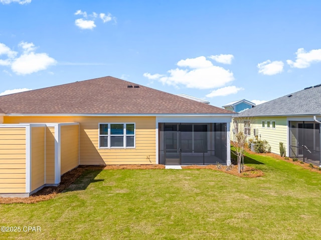 rear view of property featuring a lawn, a sunroom, and roof with shingles