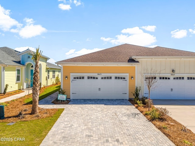 ranch-style home with board and batten siding, an attached garage, decorative driveway, and a shingled roof