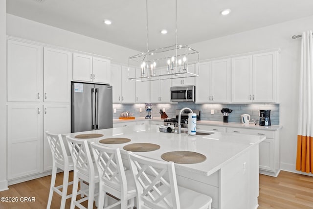 kitchen with white cabinets, appliances with stainless steel finishes, light countertops, and a sink