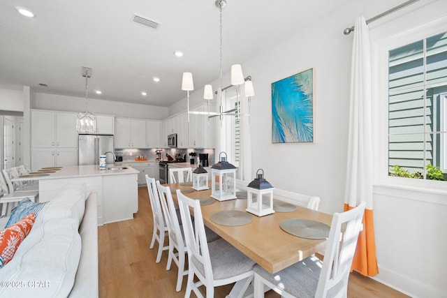 dining area featuring recessed lighting, visible vents, light wood-style flooring, and a chandelier