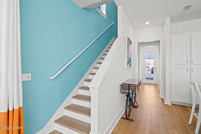 staircase featuring visible vents, baseboards, and wood finished floors